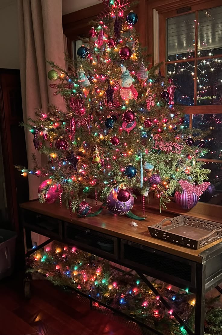 a brightly lit christmas tree in front of a window