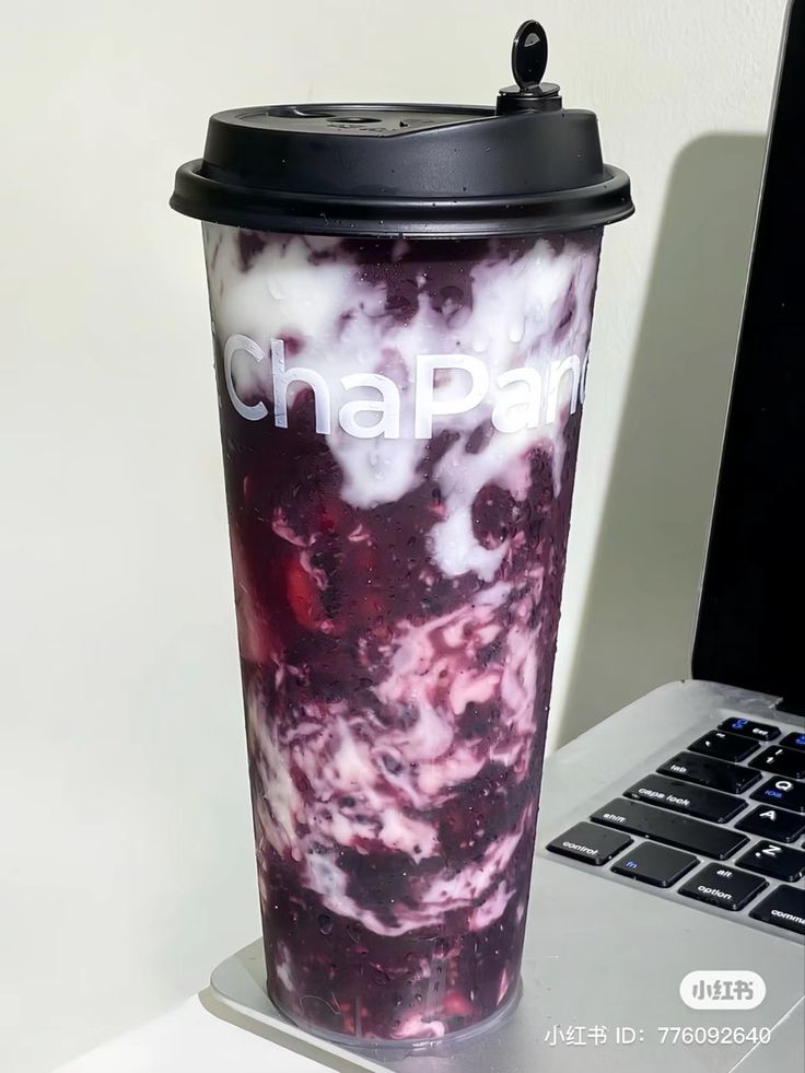 a laptop computer sitting next to a cup on top of a desk with the words chapari printed on it