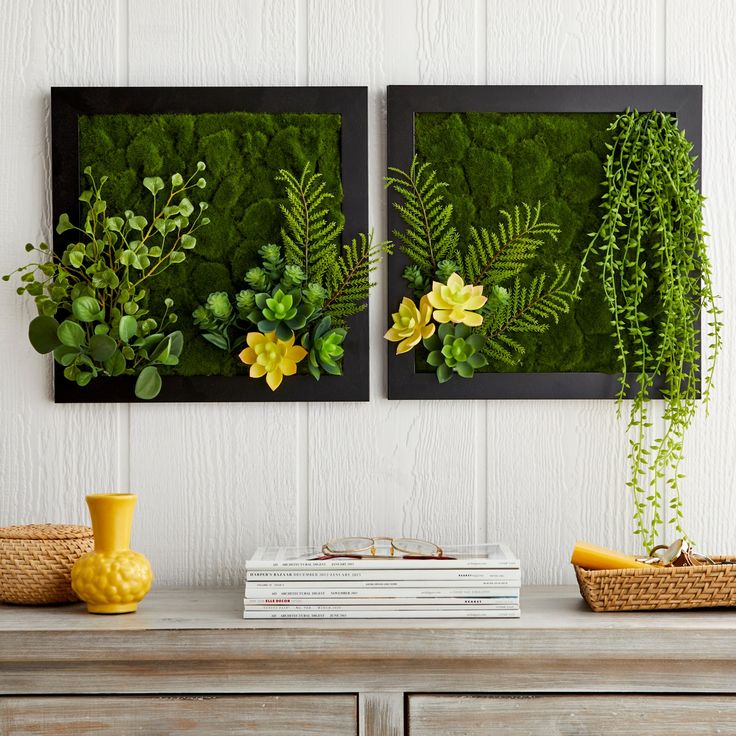 two green plants are on the wall next to a yellow vase with flowers and leaves