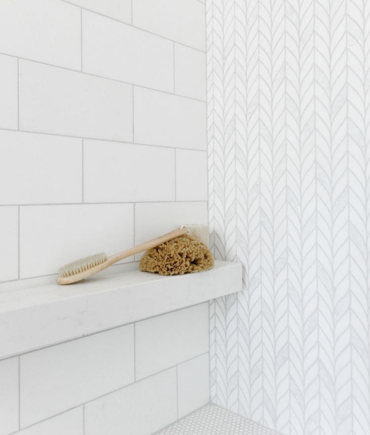 a wooden toothbrush sitting on top of a shelf in a bathroom next to a white tiled wall