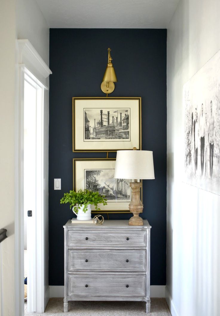 a room with blue walls and two pictures on the wall, one has a lamp