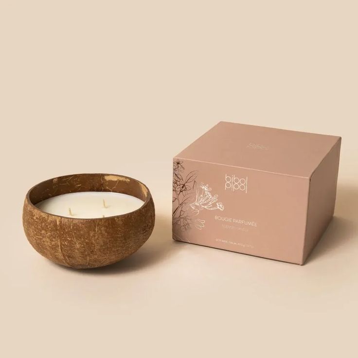 a wooden bowl next to a box with a candle in it on a white surface