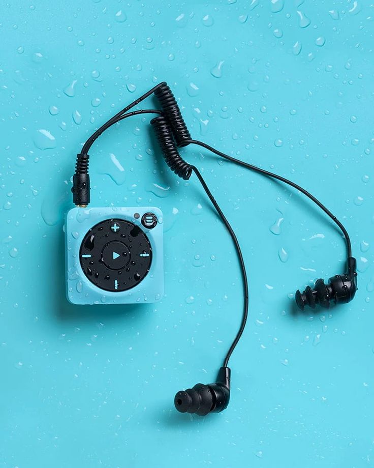 an mp3 player with ear buds attached to it on a blue surface covered in raindrops