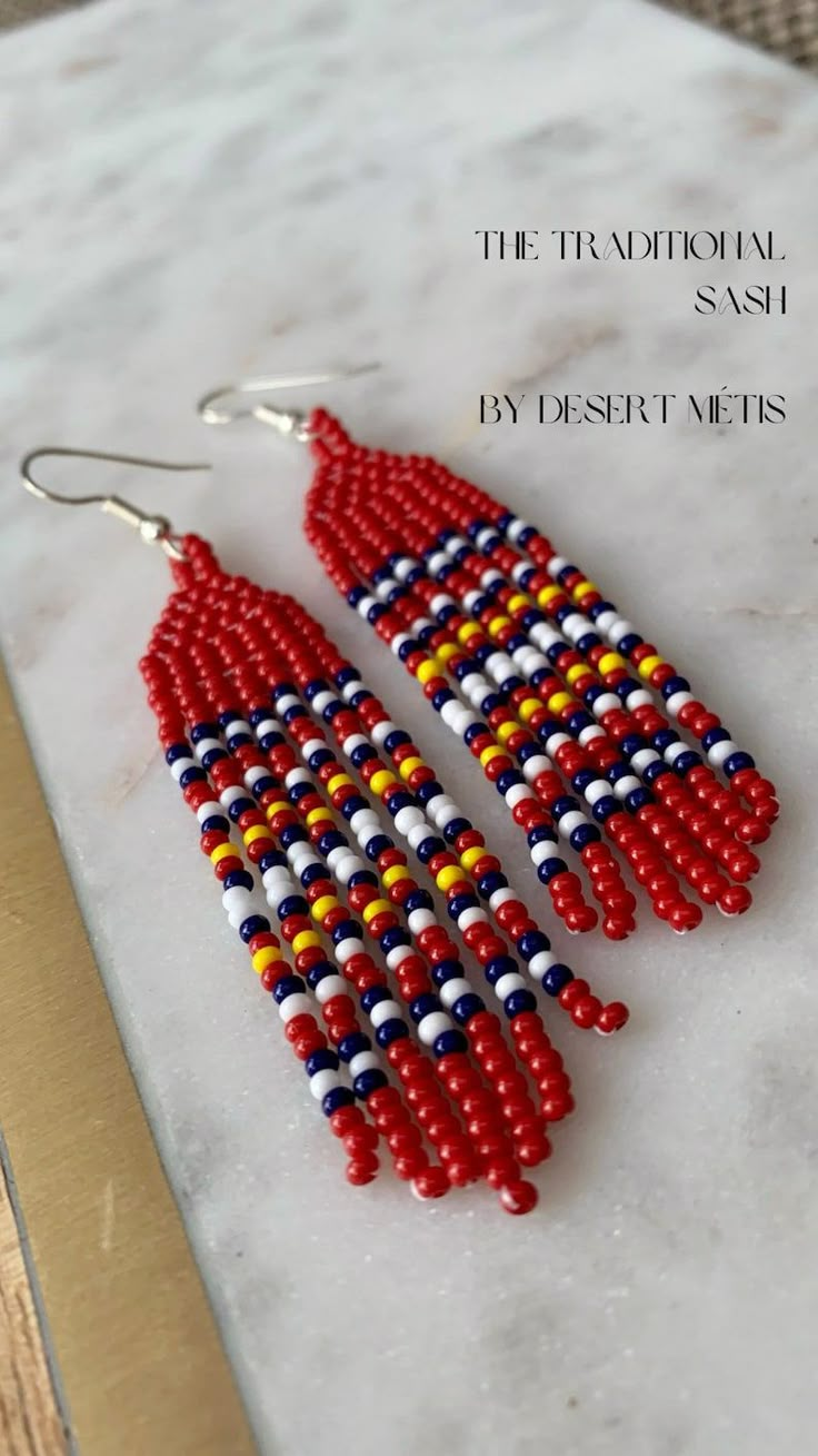 two red, white and blue beaded earrings sitting on top of a marble counter