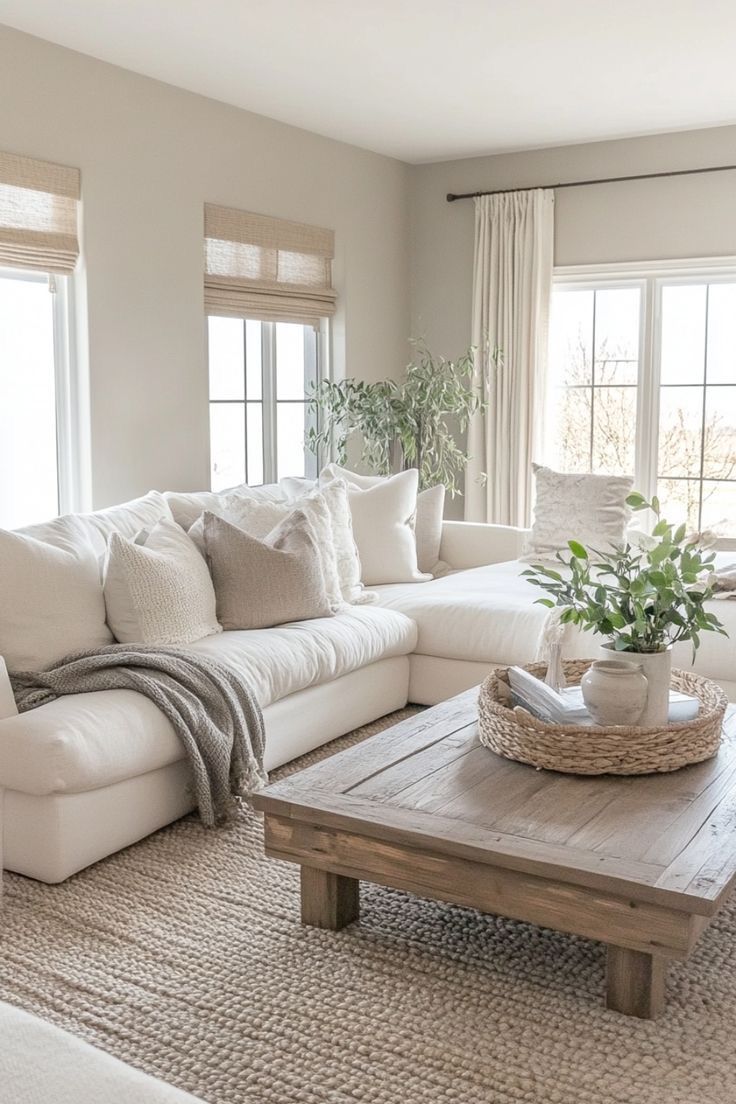 a living room filled with furniture and a wooden table in front of two large windows