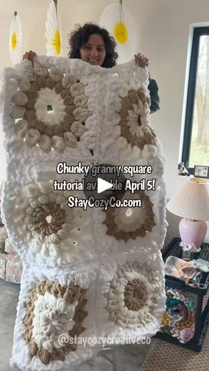 a woman standing in front of a giant crocheted owl blanket with flowers on it