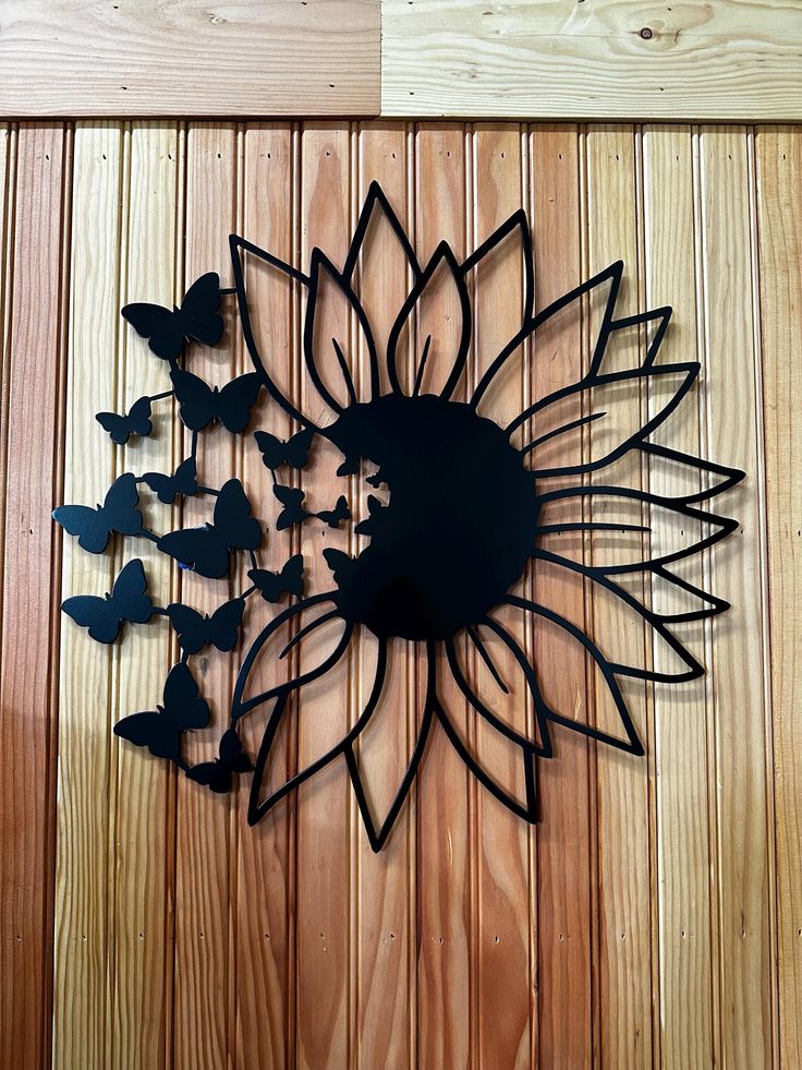 a metal sunflower clock on a wooden wall with butterflies flying in the air around it