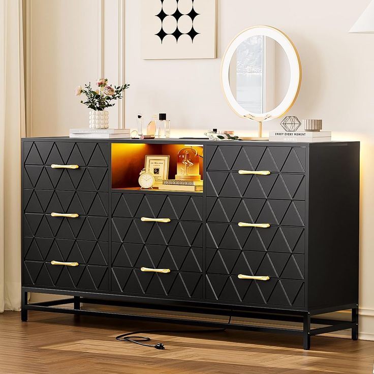 a black and gold dresser in a white room with a round mirror on the wall