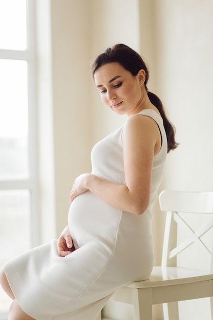 a pregnant woman sitting on a white chair