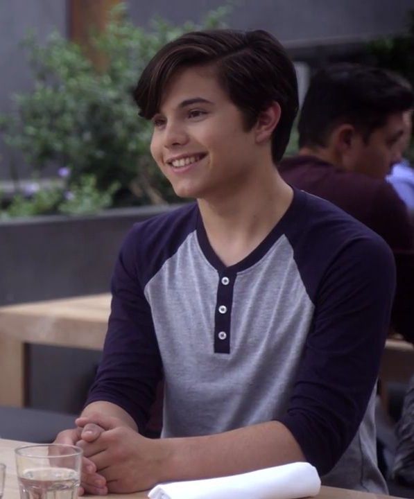 a young man sitting at a table smiling