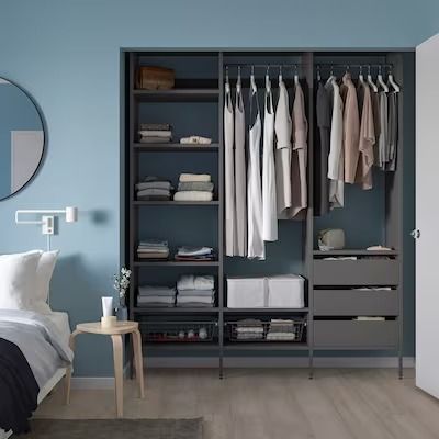 a bedroom with blue walls and an open closet that has clothes hanging on the shelves