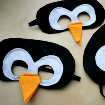 three penguin masks with white and black faces, one has an orange beak on it