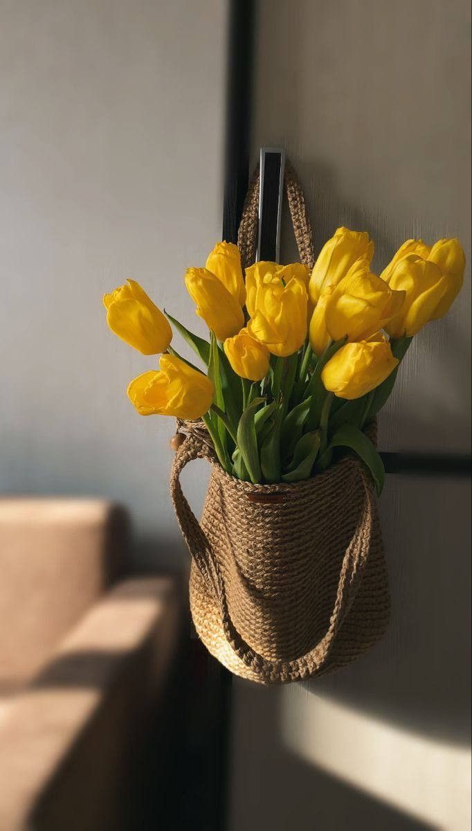 yellow tulips in a jute bag hanging from a wall