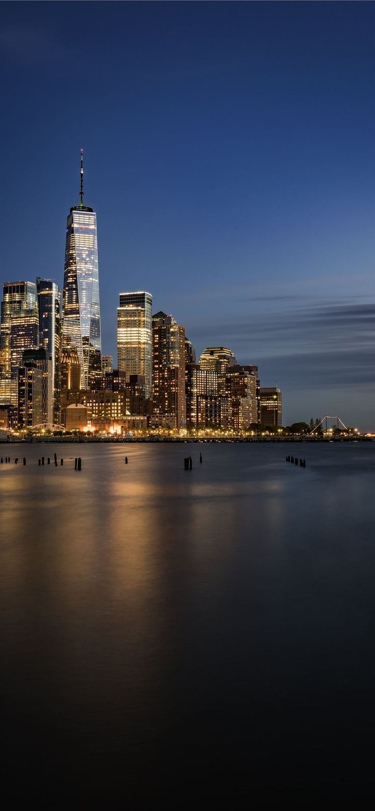 the city skyline is lit up at night, with skyscrapers in the foreground