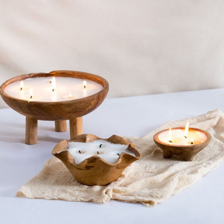 two wooden bowls filled with candles on top of a white tablecloth next to each other