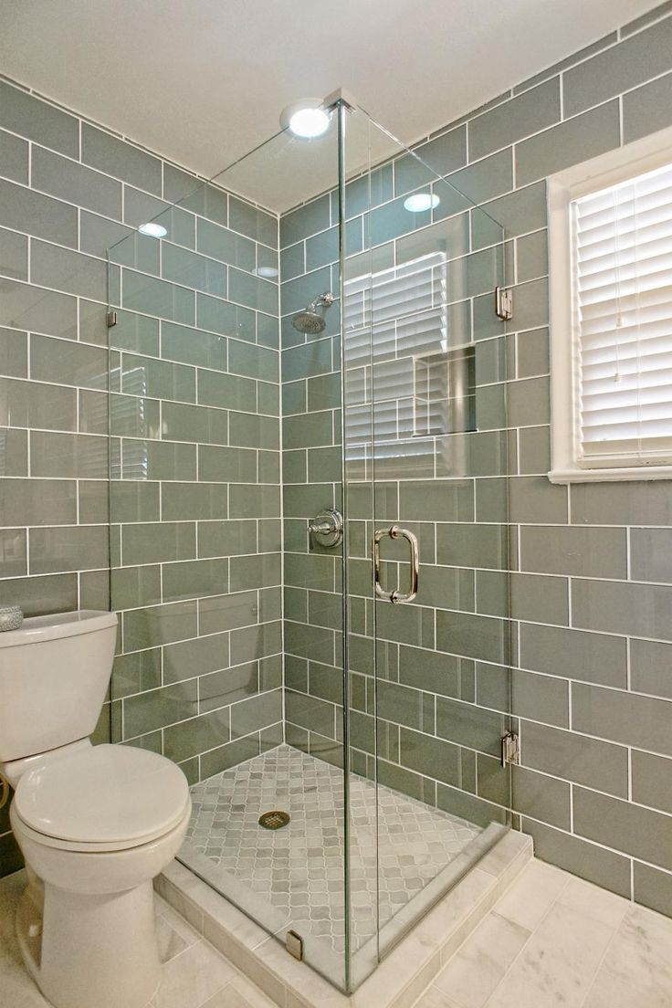 a white toilet sitting in a bathroom next to a walk - in shower stall with glass doors