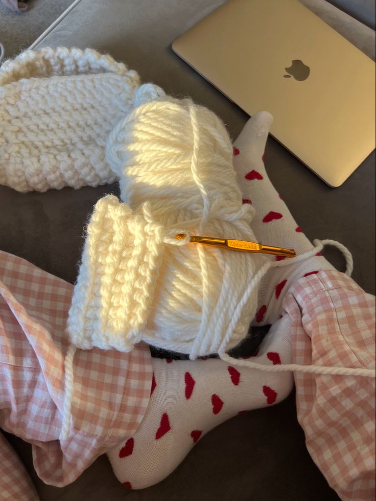 two knitted items are laying next to an apple laptop