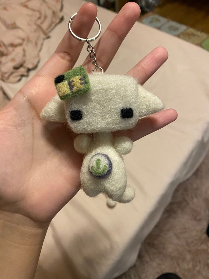 a hand holding a small white kitty keychain