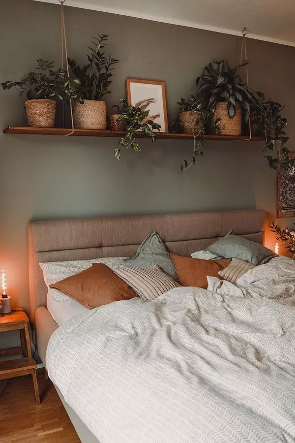 an unmade bed with plants on the shelves above it