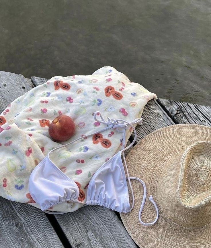 an apple is sitting on top of a blanket next to a straw hat and water