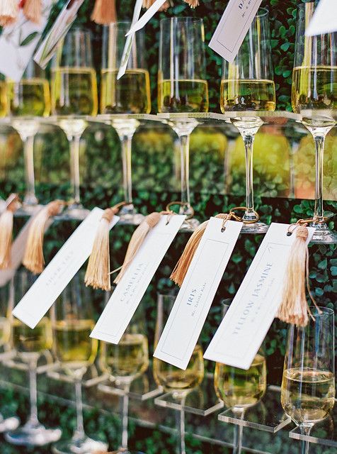 many wine glasses are lined up on the wall with tags attached to them and hanging from strings