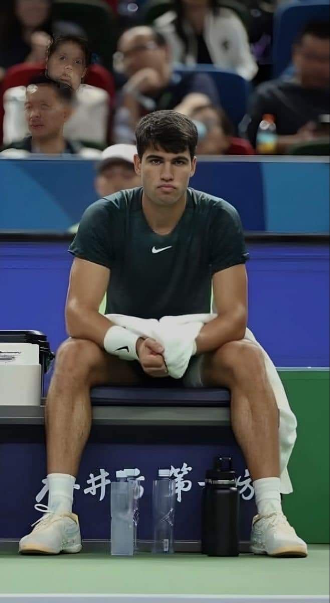 a tennis player sits on the sidelines with his towel over his face as he waits for the ball to be served