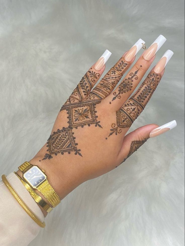 a woman's hand with henna tattoos on her left arm and two fingers