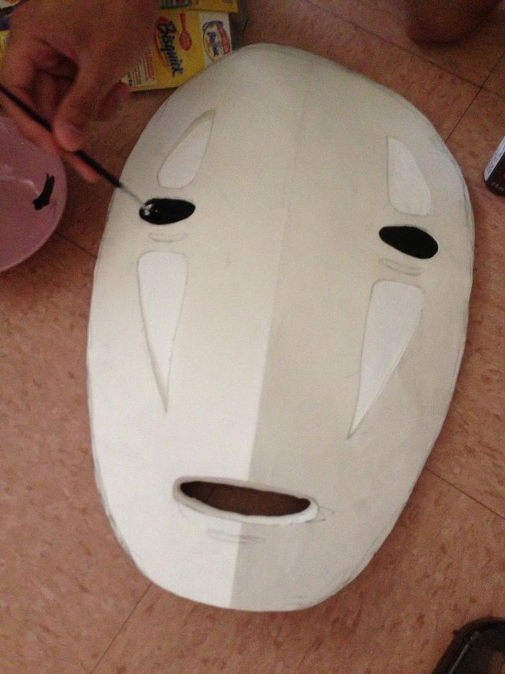 someone is making a mask out of cardboard and glues it on the floor with scissors