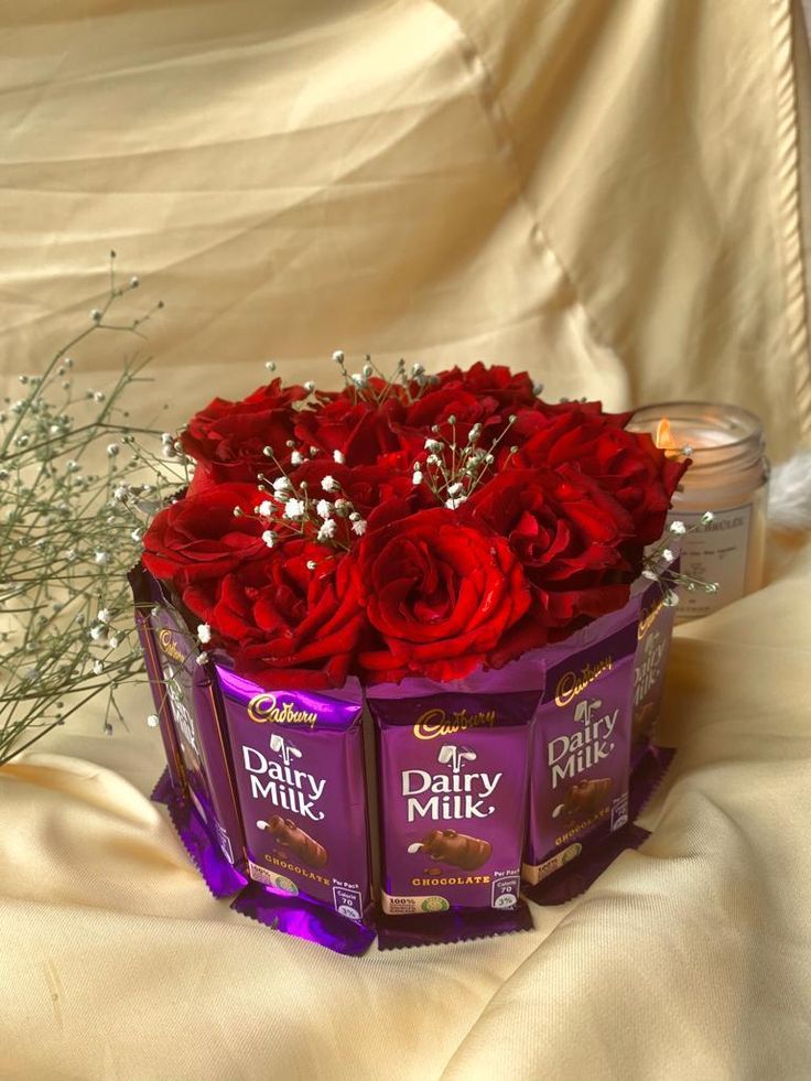 two boxes of dairy milk and red roses on a white cloth with baby's breath in the background