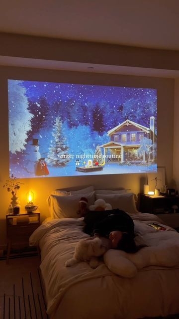 a person laying on top of a bed in front of a large projection screen above them