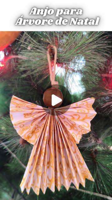 a paper angel ornament hanging from a christmas tree