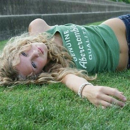 a young woman laying on the grass with her hands behind her head