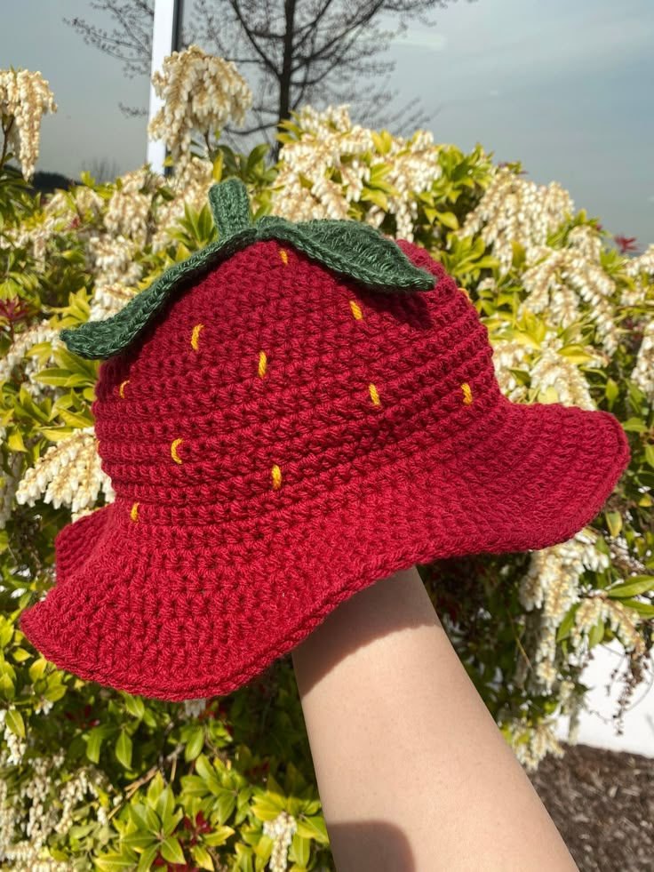 a crocheted strawberries hat is being held by a woman's hand