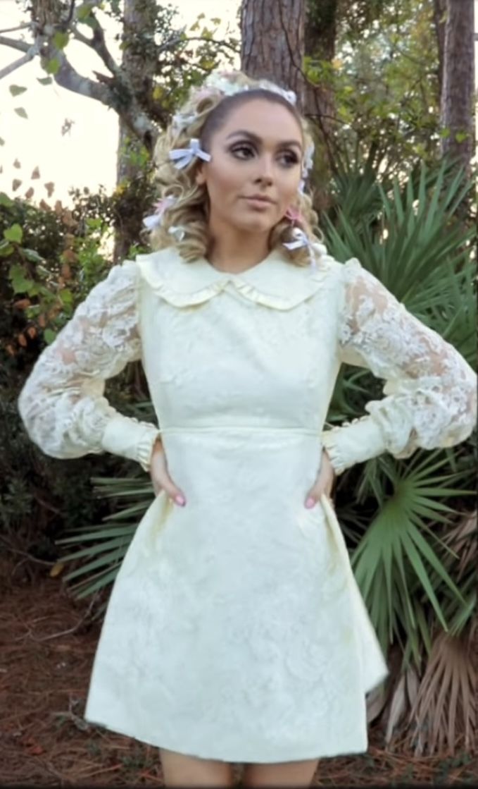 a woman in a white dress posing for the camera with her hands on her hips