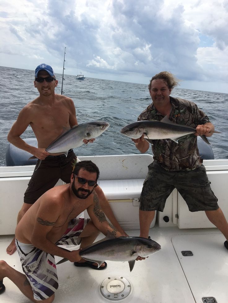 three men on a boat with fish in their hands and one man holding a fish