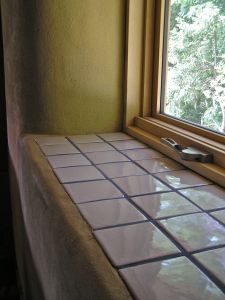 a window sill with tile on it and a tree out the window in the background