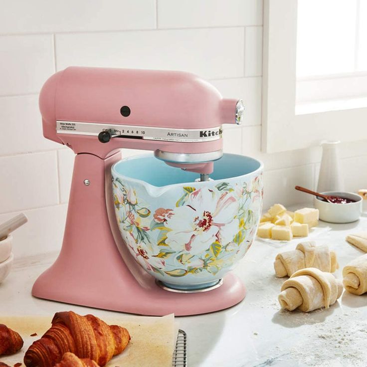 a pink mixer sitting on top of a counter next to croissants