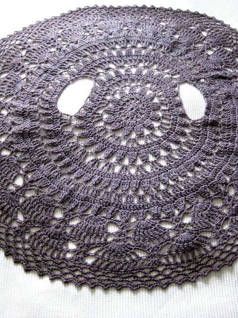 a crocheted doily with holes in the middle on a white table cloth