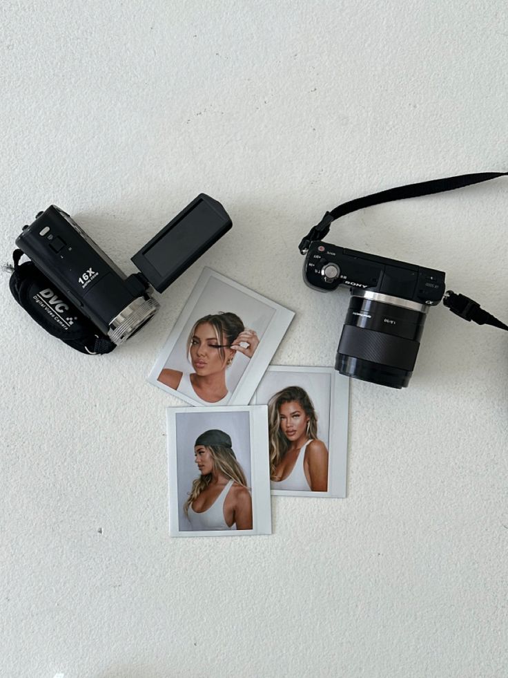 a camera and some pictures on a white surface with other things to be used in the photo