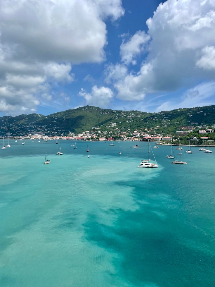 several boats floating in the ocean on a sunny day with blue skies and white clouds