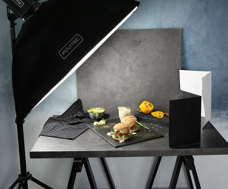 a photo studio setup with food on a table and lighting equipment in front of it