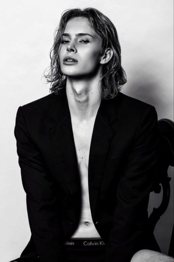 black and white photograph of a man in a suit sitting on a chair with his shirt open