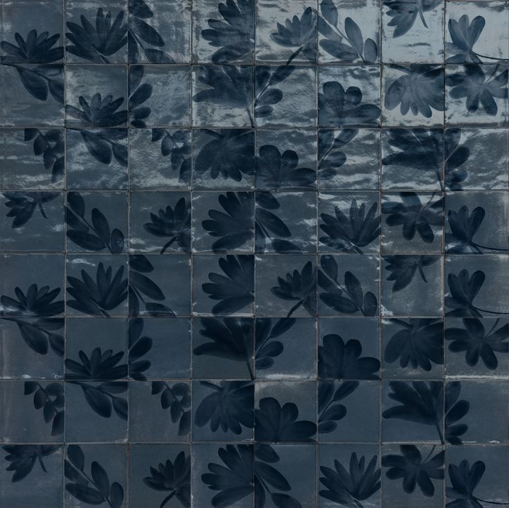 an artistic tile with leaves painted on it's sides and the bottom part of the tiles is black