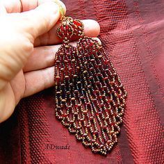 a woman is holding onto some beaded jewelry on her finger and wearing a red dress