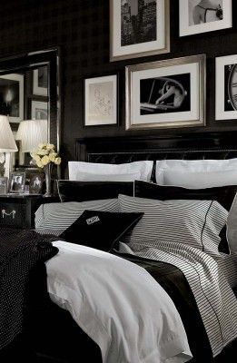 black and white bedding in a bedroom with pictures on the wall above it, along with two lamps