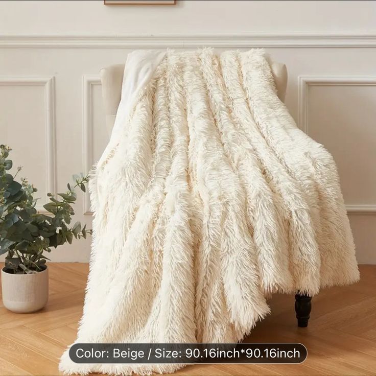 a large white blanket sitting on top of a wooden floor next to a potted plant