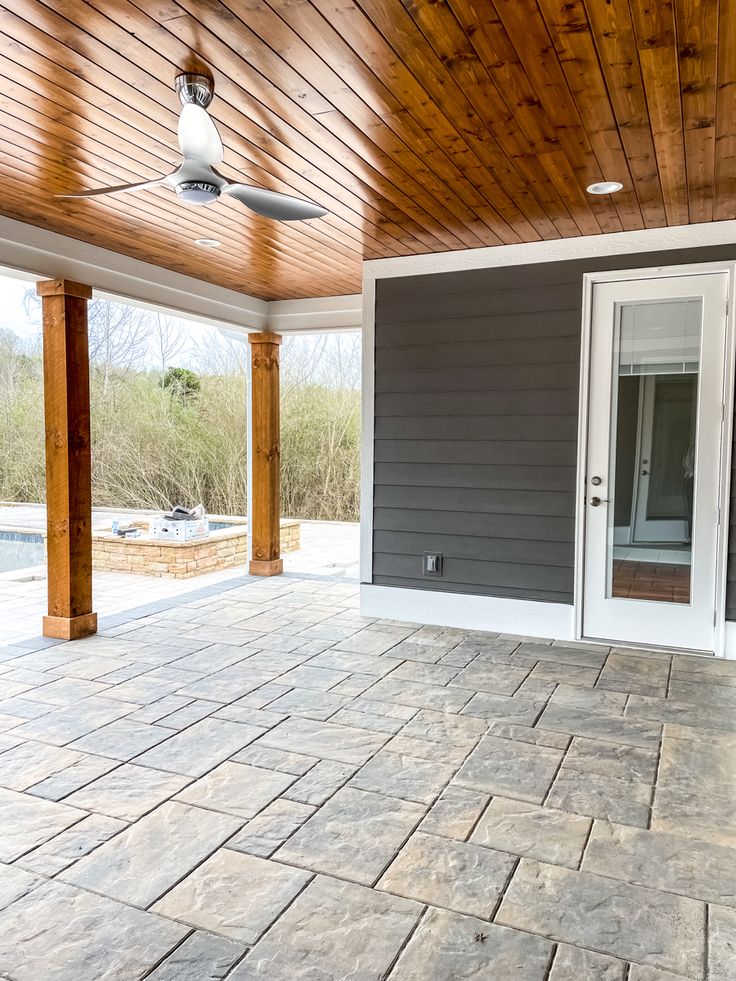 an empty patio with gray walls and wood ceilinging is seen in this image from the outside