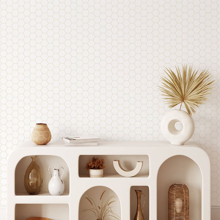 a white shelf with vases and other decorative items on it in front of a wallpapered background