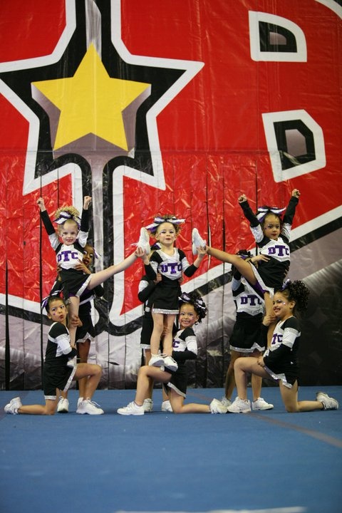 a group of cheerleaders performing in front of a large red and yellow sign