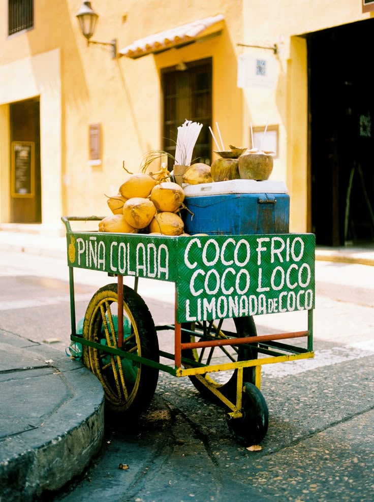 a cart filled with fruit sitting on the side of a road next to a building